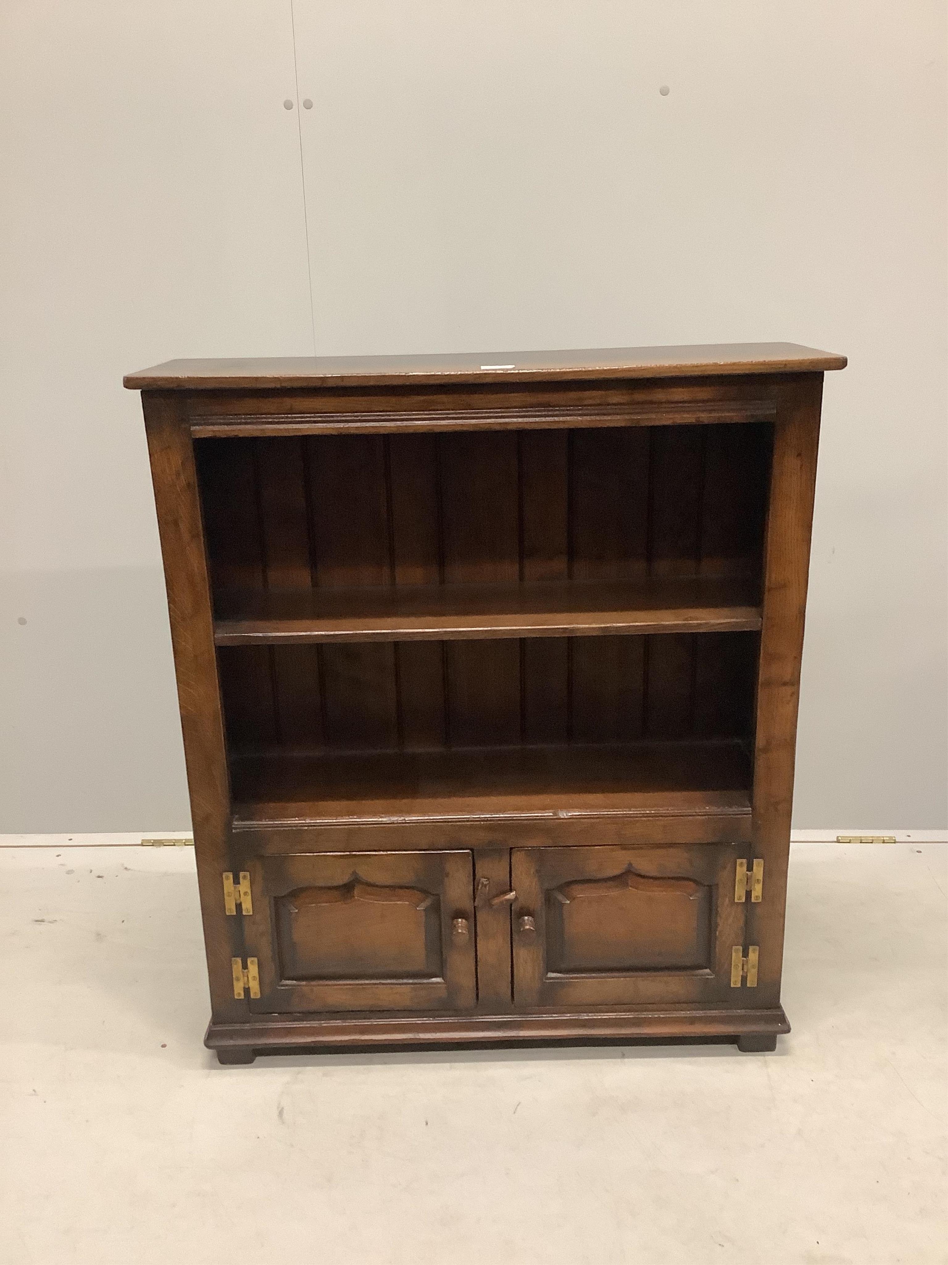 A reproduction 18th century style oak two shelf open bookcase, the base fitted with fielded panelled doors, width 84cm, depth 26cm, height 97cm. Condition - good